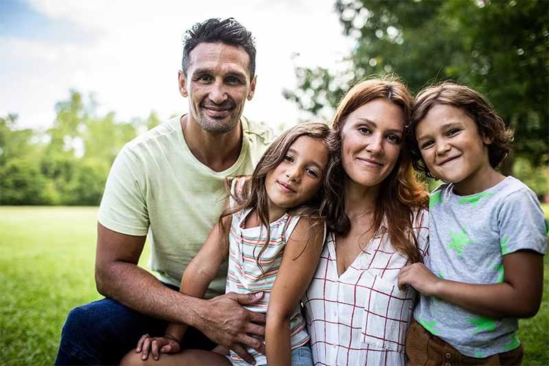 A family of four embraces in a park