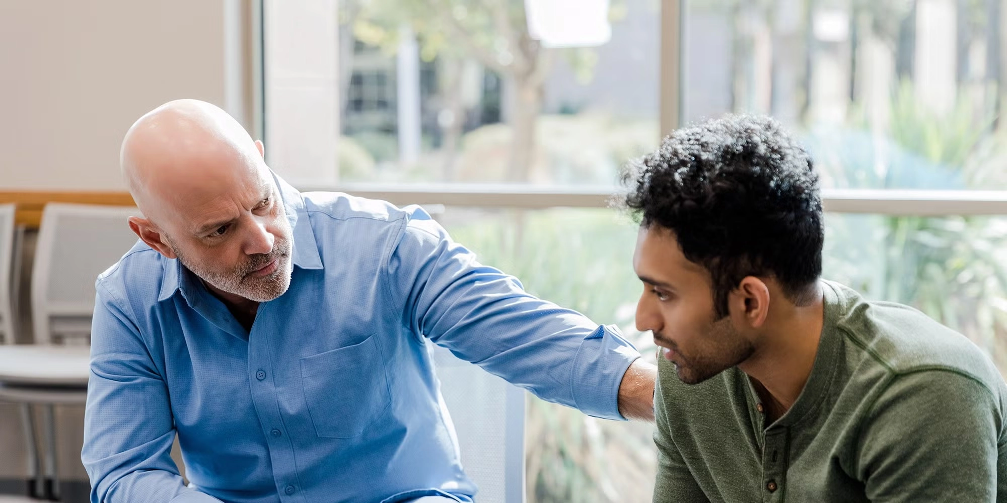 A male counselor consoles a man in his office