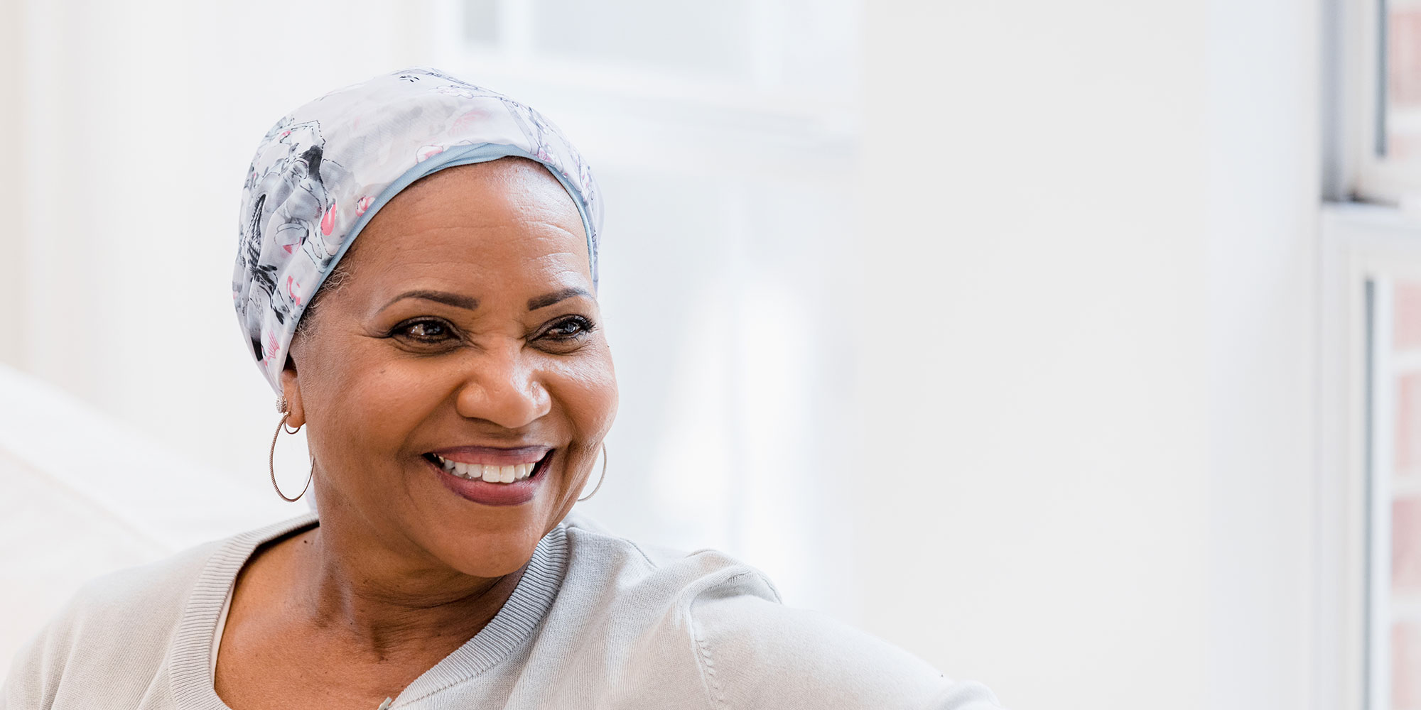 A beautiful woman wearing a head wrap gazes out a window