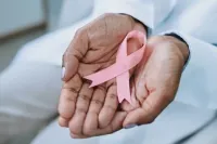 A pair of hands holds a pink breast cancer ribbon